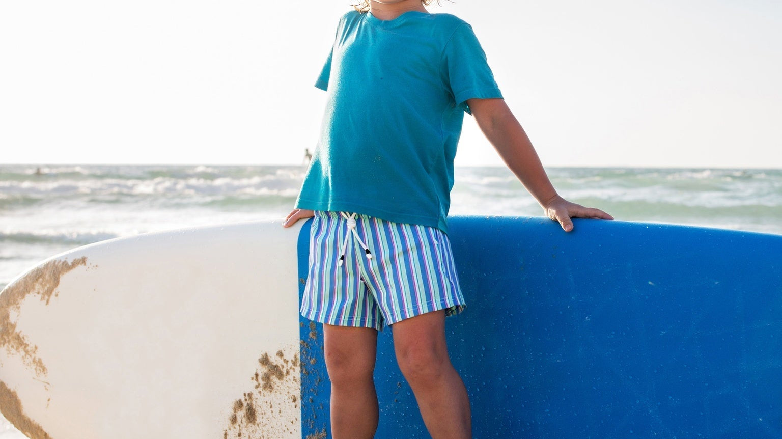 Happy kids wearing Surfcuz swim trunks playing at the beach, enjoying the sun and waves