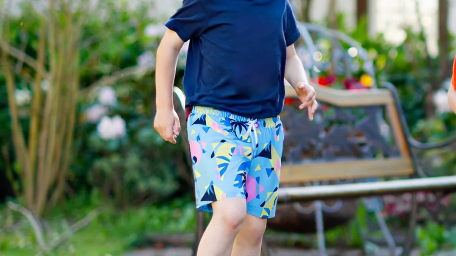 Child wearing Surfcuz kids swim trunks running from the playground to the pool, showing comfort and versatility