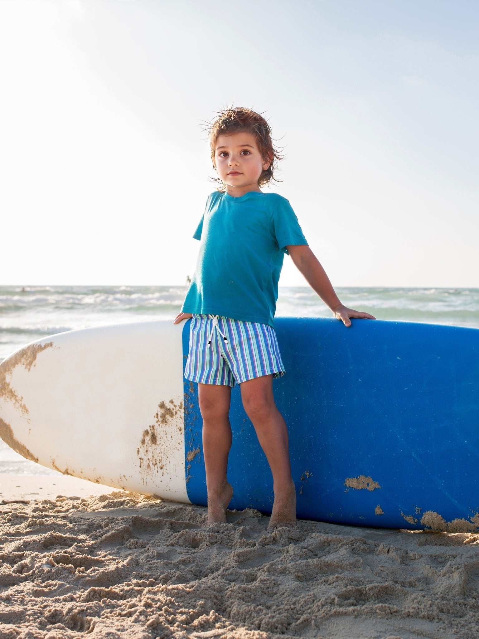 Happy kids wearing Surfcuz swim trunks playing at the beach, enjoying the sun and waves
