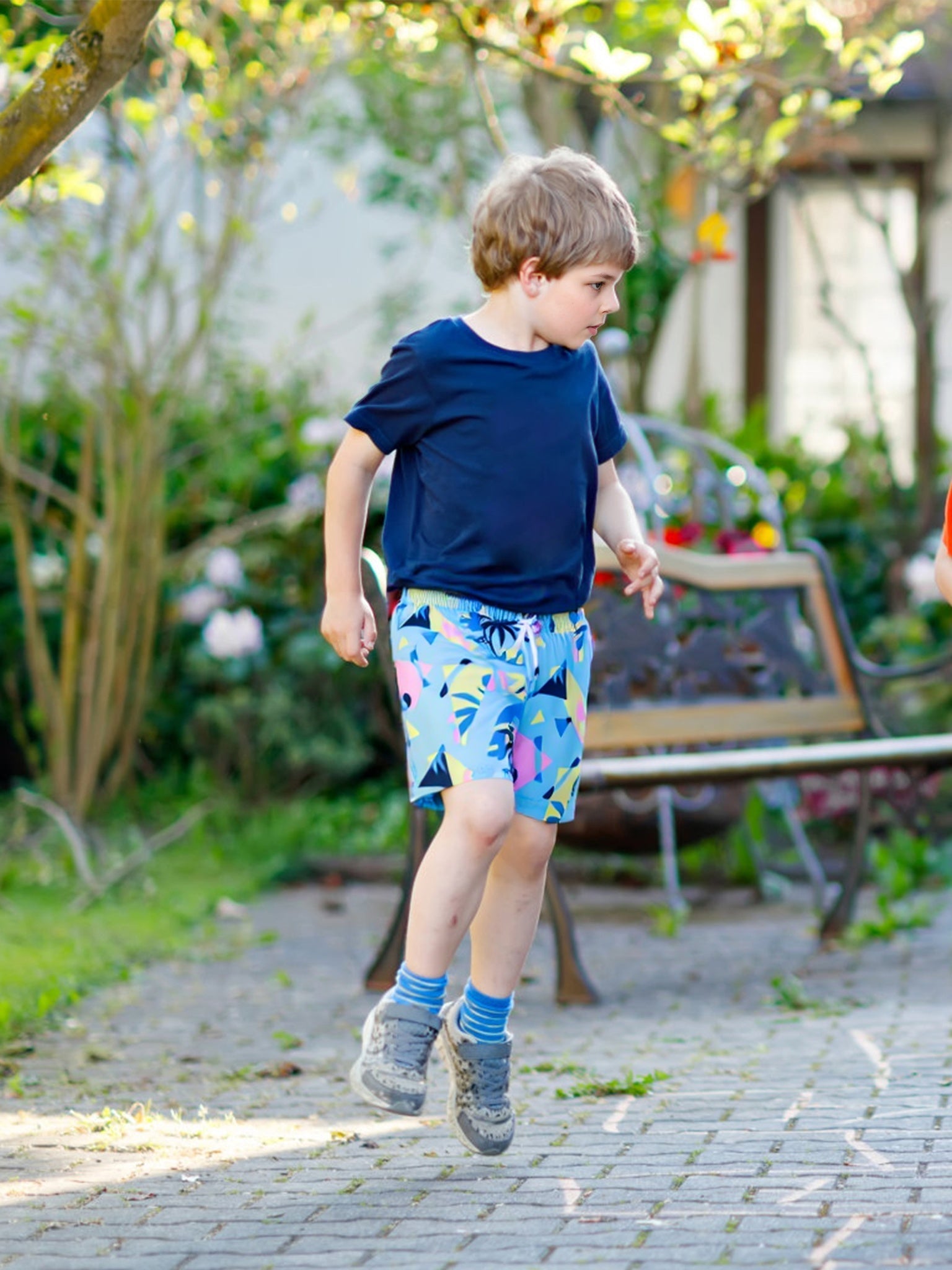 Child wearing Surfcuz kids swim trunks running from the playground to the pool, showing comfort and versatility